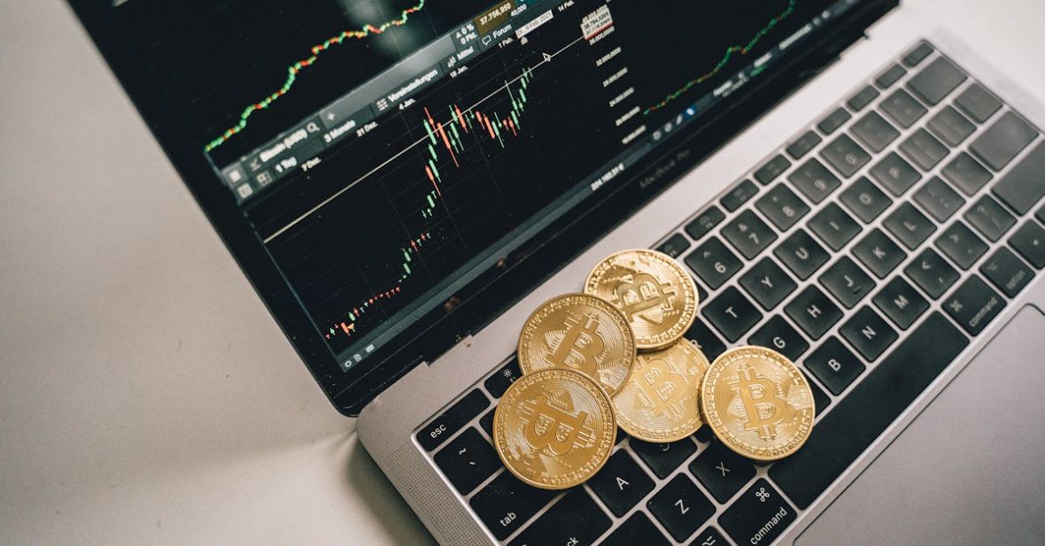 golden-bitcoin-coins-placed-on-a-laptop-keyboard-with-trading-chart-displayed-on-the-screen